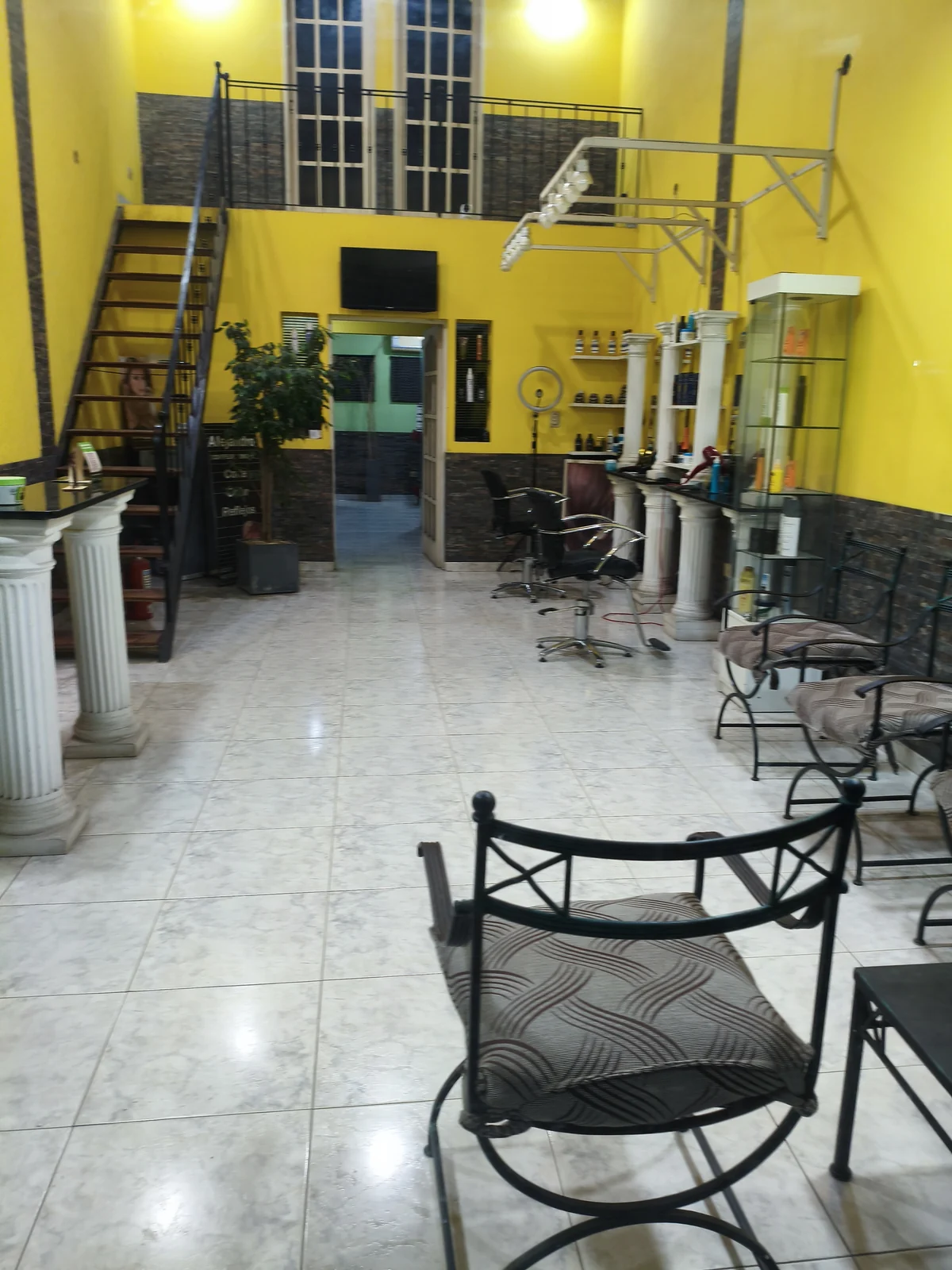 Las columnas blancas de la recepción y la escalera negra contra la pared amarilla